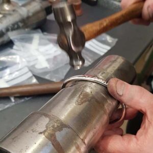 Putting a hammered finish to a silver bangle at Thorntons Jewellers workshop in Kettering